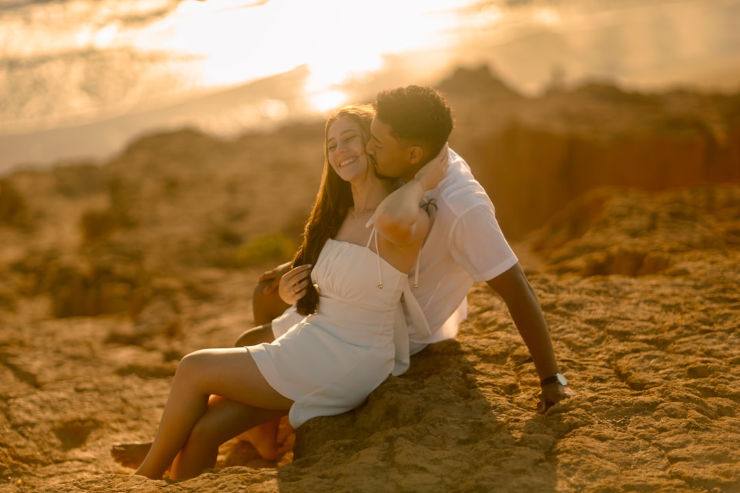 A couple sharing a romantic embrace on coastal rocks at sunset