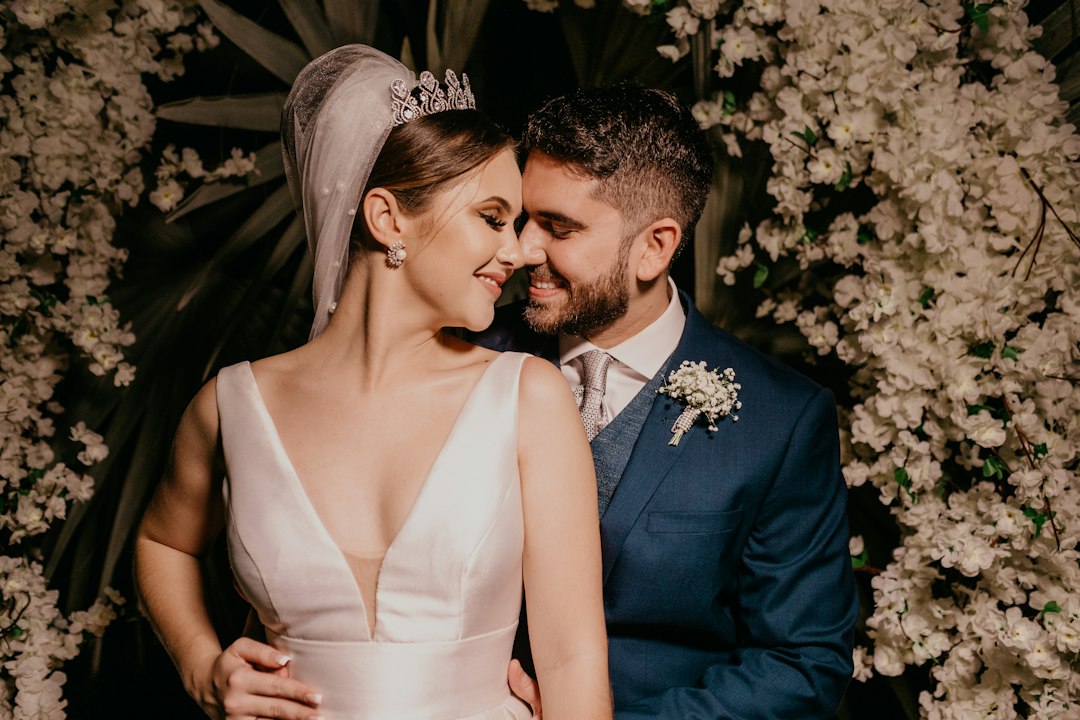 A wedding couple embracing beneath white flowers